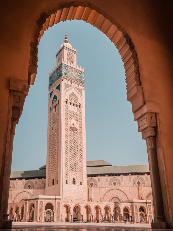 10 Day Morocco Tour From Casablanca 2 Elegant view of the Hassan II Mosque minaret through an ornate archway in Casablanca, Morocco.10-day Morocco tour from Casablanca