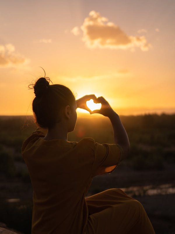 4 Days Tour From Marrakech To Fes 3 Silhouette of a person forming a heart with hands against a Morocco sunset.