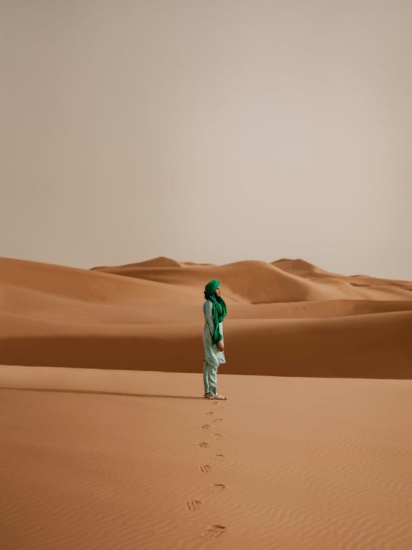 Discover Morocco 3 Days Marrakech To Fes Magic 8 A solitary figure stands in the vast desert dunes of Merzouga, Morocco, creating a serene and contemplative scene.